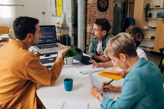 IT Programmers gather around the desktop computer to develop MDR software